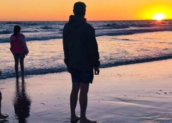 Familia contemplando el atardecer sobre el mar