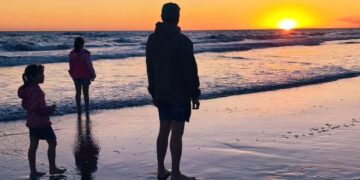 Familia contemplando el atardecer sobre el mar